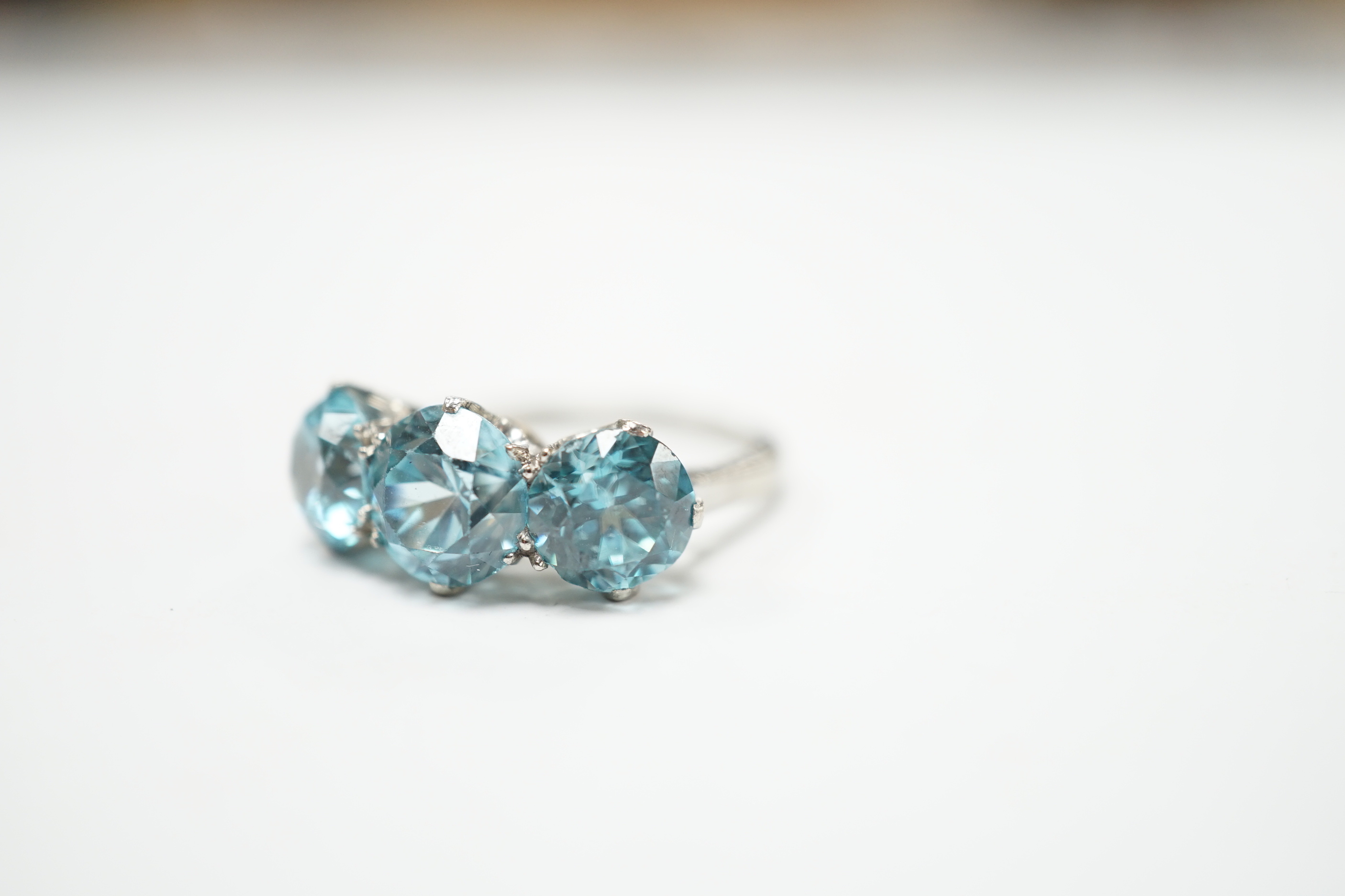 A white metal and three stone blue zircon set dress ring, size L, gross weight 4.1 grams.
